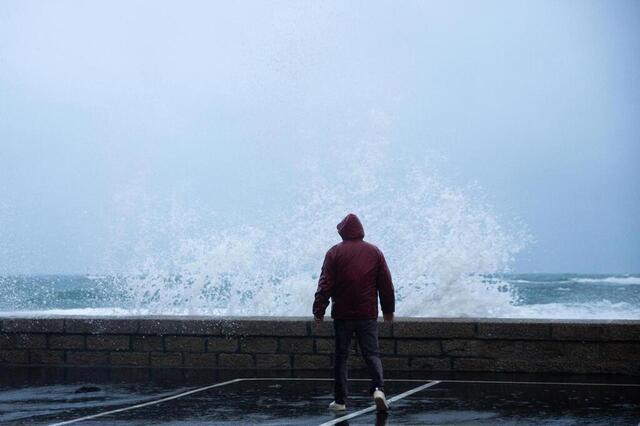 photo un promeneur regarde les vagues sur la jetée à proximité de la criée au port de pêche du guilvinec (finistère) mercredi soir, au début de la tempête « ciaran ». © guillaume saligot / ouest-france